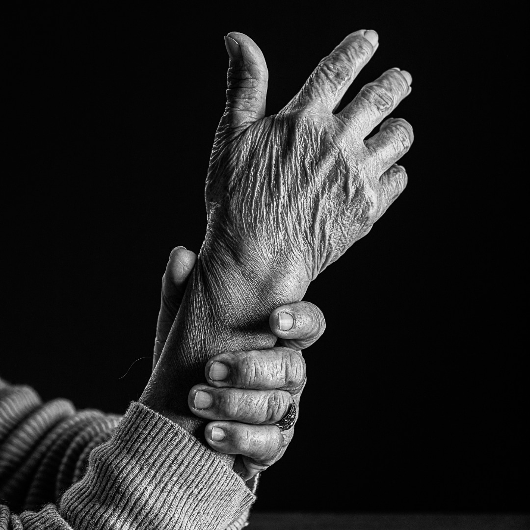 Black and white image of someone holding their wrist to stop tremors