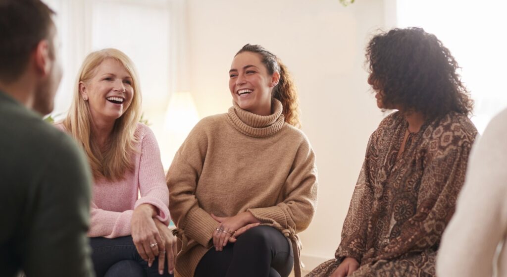 happy women in group support session|happy woman in support session|happy group in support session|happy woman in support session|group of people in support session|doctor holding brain scans|doctor speaking with patient|happy woman|doctor speaking with patient about brain scans|doctor speaking with patient