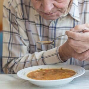 man with Parkinson's eating soup