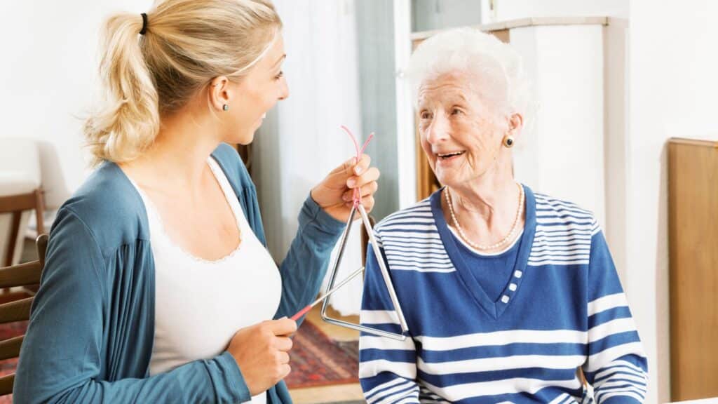 young woman playing triangle for old woman with Alzheimer's