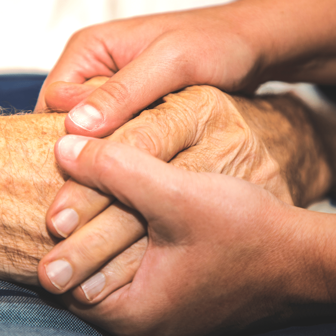 A young person's hands holding an older person's hands