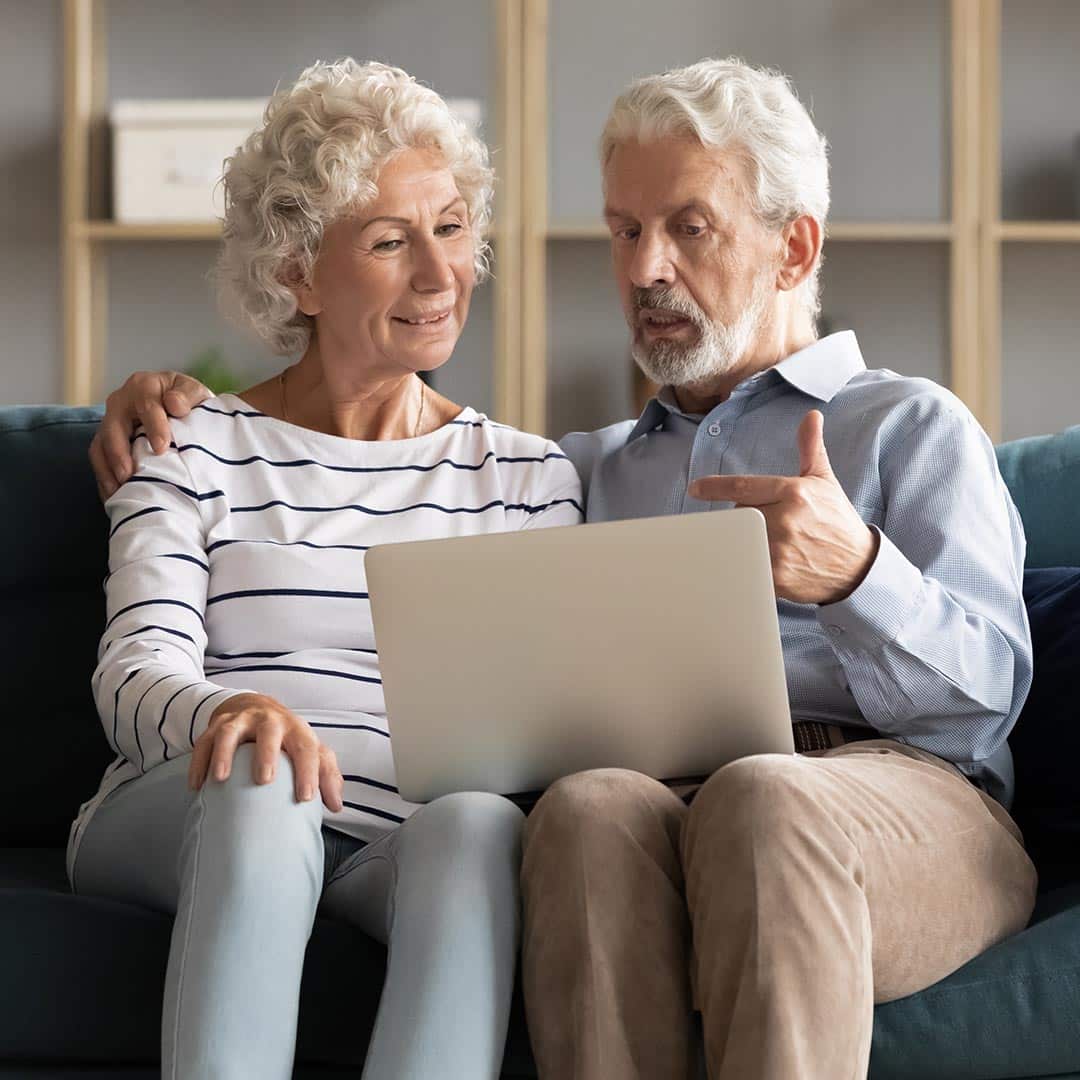 Senior couple talking and using a laptop