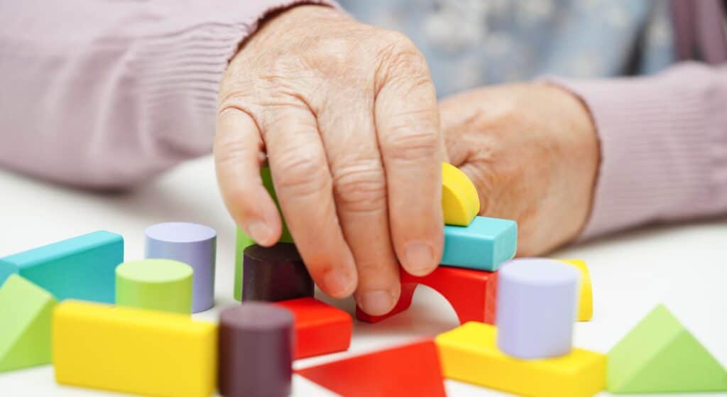 person with Alzheimer's using blocks to help with memory||An elderly man with Alzheimer's|person trying to complete a crossword puzzle|two women talking|a woman helping an Alzheimer's patient