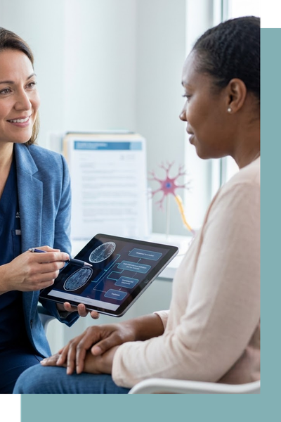 A specialist using a tablet to explain advanced brain wave readouts to a patient in a modern, light-filled consultation room.